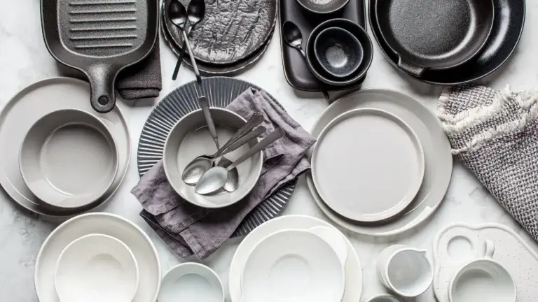 A variety of ceramic dishes and utensils displayed on a sleek marble countertop.