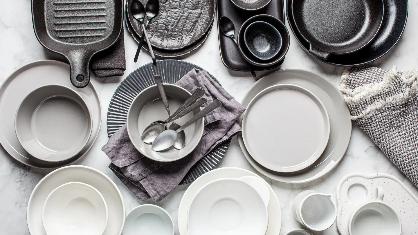 A variety of ceramic dishes and utensils displayed on a sleek marble countertop.
